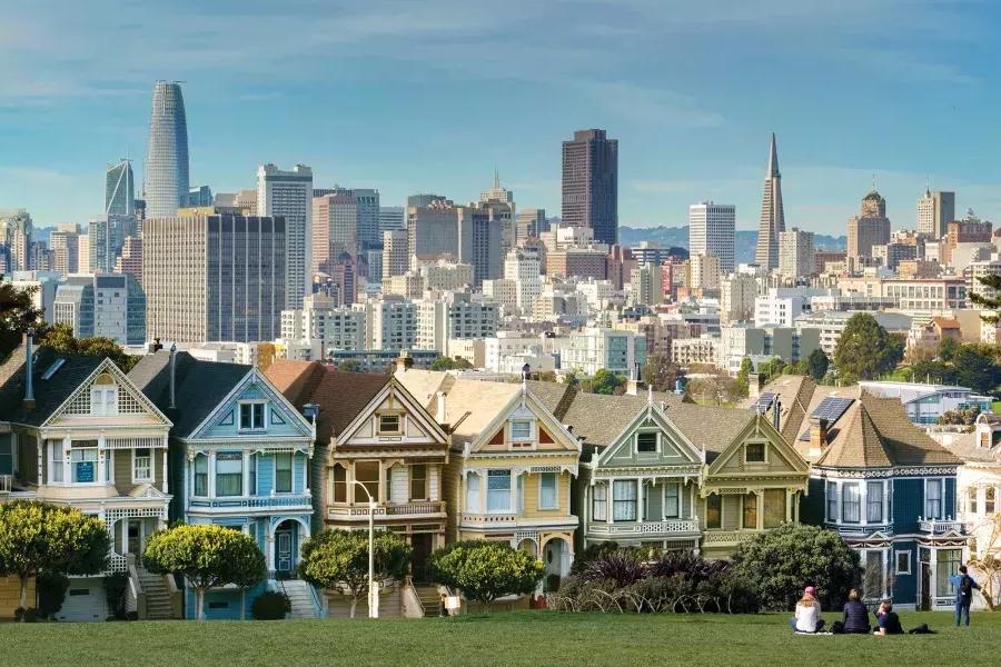 Picnickers sit on the grass at Alamo Square Park with the 涂女士 and 贝博体彩app skyline in the background.