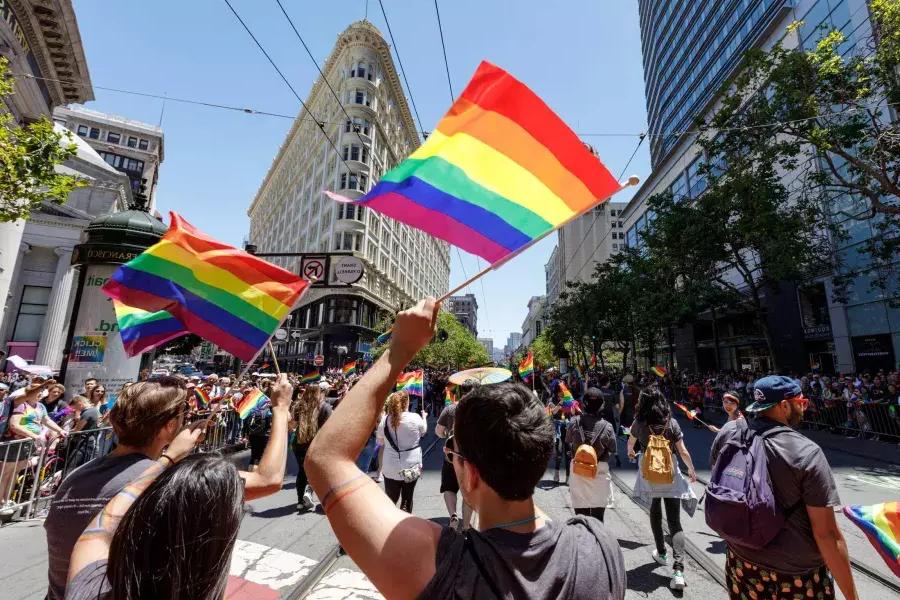 Passanten der San Francisco Pride Parade schwenken Regenbogenfahnen.