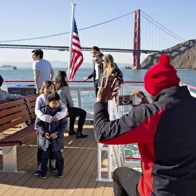 A family enjoys a cruise on the bay, passing the 金门大桥.